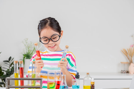 little girl Wear a brightly colored shirt working with test tube science experiment in white roomの写真素材