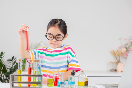 little girl Wear a brightly colored shirt working with test tube science experiment in white roomの写真素材