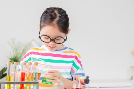 little girl Wear a brightly colored shirt working with test tube science experiment in white roomの写真素材