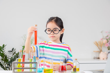 little girl Wear a brightly colored shirt working with test tube science experiment in white roomの写真素材