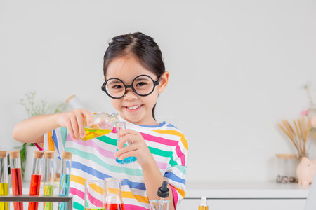 little girl Wear a brightly colored shirt working with test tube science experiment in white roomの写真素材
