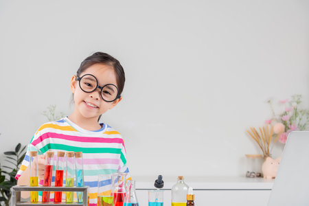 little girl Wear a brightly colored shirt working with test tube science experiment in white roomの写真素材