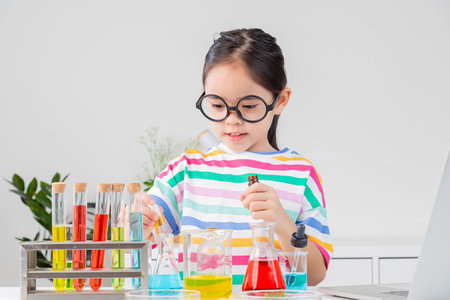 little girl Wear a brightly colored shirt working with test tube science experiment in white roomの写真素材