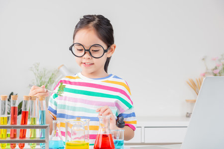 little girl Wear a brightly colored shirt working with test tube science experiment in white roomの写真素材