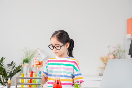 little girl Wear a brightly colored shirt working with test tube science experiment in white roomの写真素材