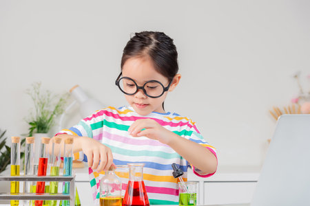 little girl Wear a brightly colored shirt working with test tube science experiment in white roomの写真素材