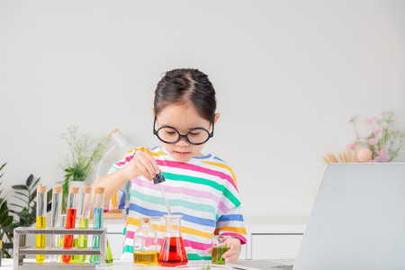 little girl Wear a brightly colored shirt working with test tube science experiment in white roomの写真素材