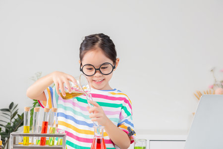 little girl Wear a brightly colored shirt working with test tube science experiment in white roomの写真素材