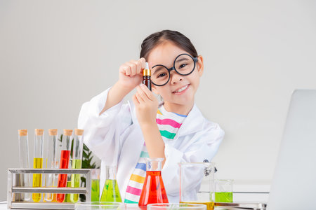 little girl Wear a science ground shirt working with test tube science experiment in white roomの写真素材