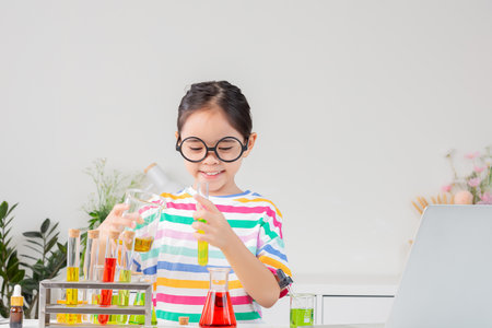 little girl Wear a brightly colored shirt working with test tube science experiment in white roomの写真素材