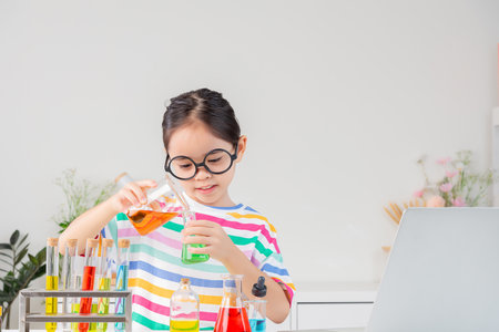 little girl Wear a brightly colored shirt working with test tube science experiment in white roomの写真素材