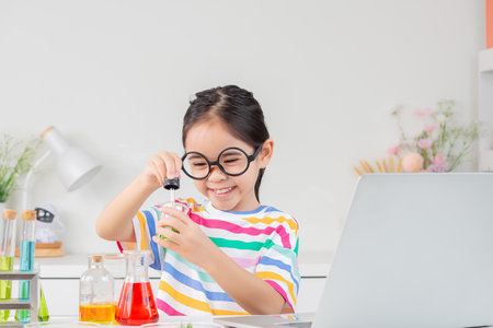 little girl Wear a brightly colored shirt working with test tube science experiment in white roomの写真素材