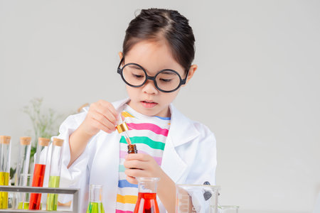 little girl Wear a science ground shirt working with test tube science experiment in white roomの写真素材