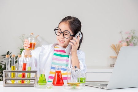 little girl Wear a science ground shirt working with test tube science experiment in white roomの写真素材