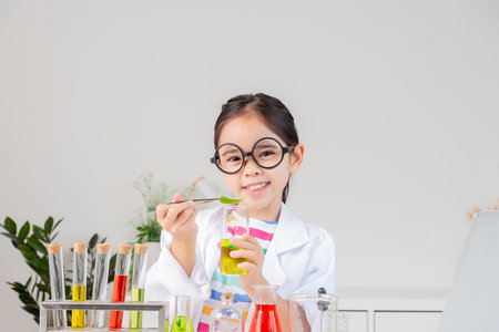 little girl Wear a science ground shirt working with test tube science experiment in white roomの写真素材