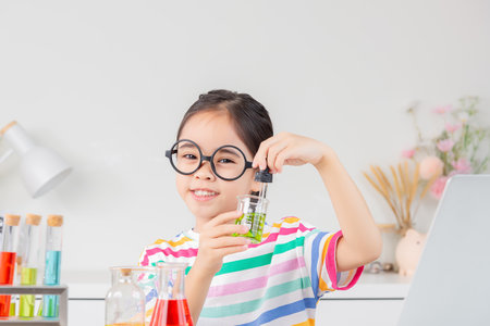 little girl Wear a brightly colored shirt working with test tube science experiment in white roomの写真素材