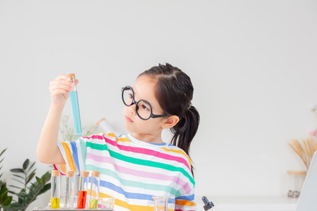 little girl Wear a brightly colored shirt working with test tube science experiment in white roomの写真素材