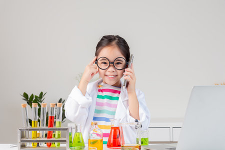 little girl Wear a science ground shirt working with test tube science experiment in white roomの写真素材