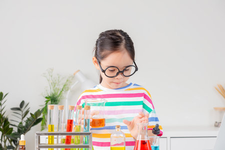 little girl Wear a brightly colored shirt working with test tube science experiment in white roomの写真素材