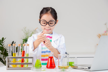 little girl Wear a science ground shirt working with test tube science experiment in white roomの写真素材