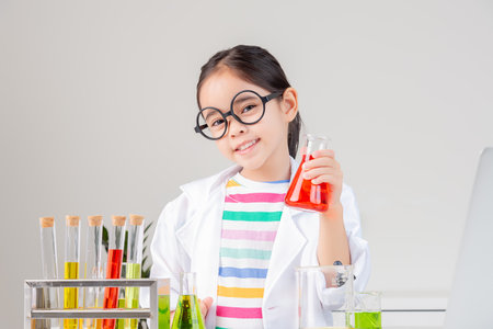 little girl Wear a science ground shirt working with test tube science experiment in white roomの写真素材