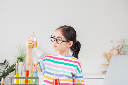 little girl Wear a brightly colored shirt working with test tube science experiment in white roomの写真素材