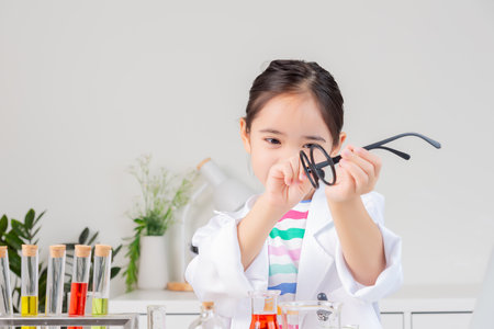 little girl Wear a science ground shirt working with test tube science experiment in white roomの写真素材