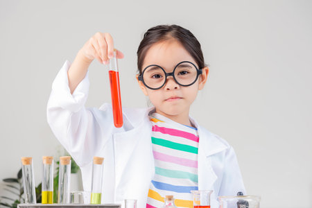 little girl Wear a science ground shirt working with test tube science experiment in white roomの写真素材