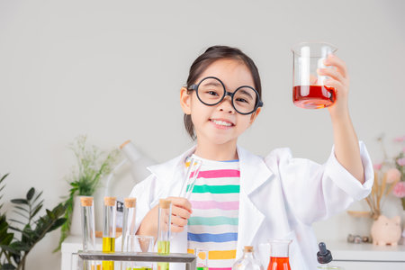 little girl Wear a science ground shirt working with test tube science experiment in white roomの写真素材