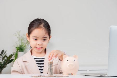 little girl wearing a cream suit analyzing coins concept of finance and investment in white roomの写真素材