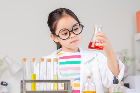 little girl Wear a science ground shirt working with test tube science experiment in white roomの写真素材