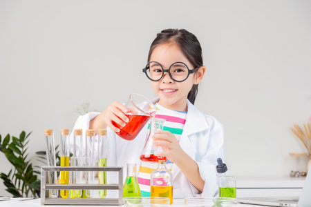 little girl Wear a science ground shirt working with test tube science experiment in white roomの写真素材