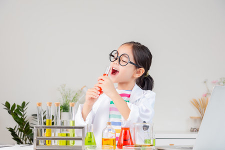 little girl Wear a science ground shirt working with test tube science experiment in white roomの写真素材