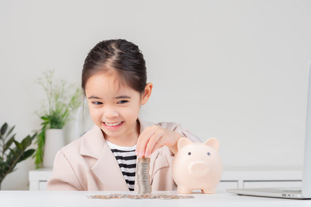little girl wearing a cream suit analyzing coins concept of finance and investment in white roomの写真素材