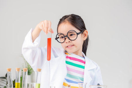 little girl Wear a science ground shirt working with test tube science experiment in white roomの写真素材