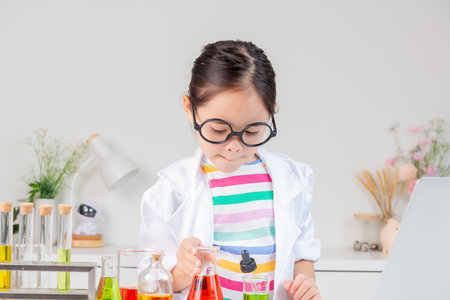 little girl Wear a science ground shirt working with test tube science experiment in white roomの写真素材