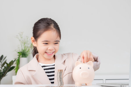 little girl wearing a cream suit analyzing coins concept of finance and investment in white roomの写真素材