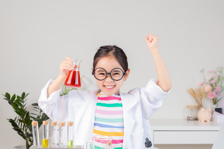little girl Wear a science ground shirt working with test tube science experiment in white roomの写真素材