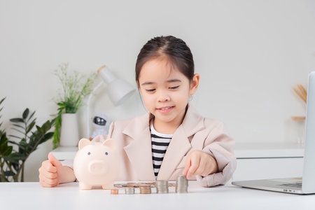 little girl wearing a cream suit analyzing coins concept of finance and investment in white roomの写真素材