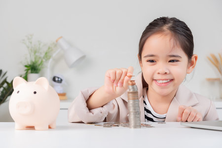 little girl wearing a cream suit analyzing coins concept of finance and investment in white roomの写真素材