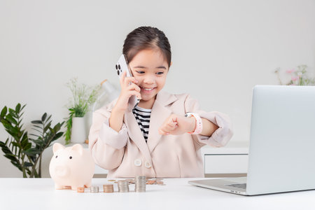 little girl wearing a cream suit analyzing coins concept of finance and investment in white roomの写真素材