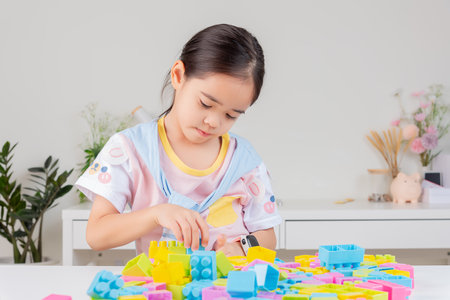 little girl wearing a bright shirt is happy Playing colorful block puzzles. in the white roomの写真素材