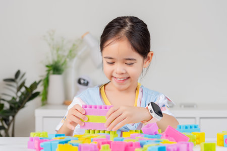 little girl wearing a bright shirt is happy Playing colorful block puzzles. in the white roomの写真素材
