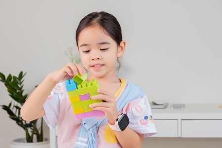 little girl wearing a bright shirt is happy Playing colorful block puzzles. in the white roomの写真素材