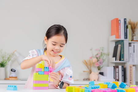 little girl wearing a bright shirt is happy Playing colorful block puzzles. in the white roomの写真素材