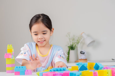 little girl wearing a bright shirt is happy Playing colorful block puzzles. in the white roomの写真素材