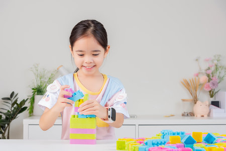 little girl wearing a bright shirt is happy Playing colorful block puzzles. in the white roomの写真素材