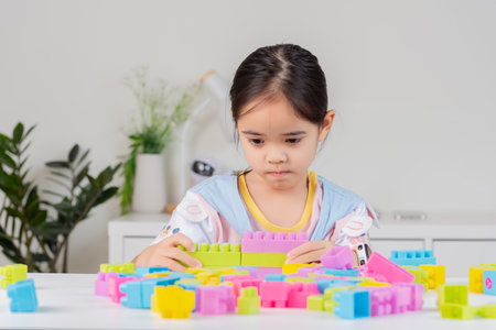 little girl wearing a bright shirt is happy Playing colorful block puzzles. in the white roomの写真素材