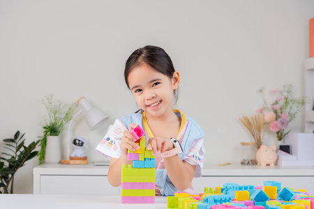 little girl wearing a bright shirt is happy Playing colorful block puzzles. in the white roomの写真素材