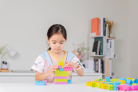 little girl wearing a bright shirt is happy Playing colorful block puzzles. in the white roomの写真素材